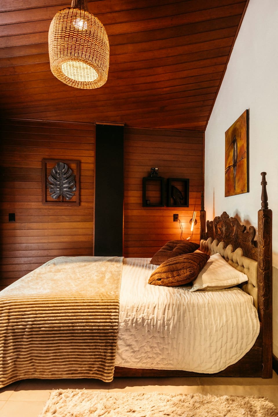 Un letto con lenzuola neutre in una camera da letto in legno.