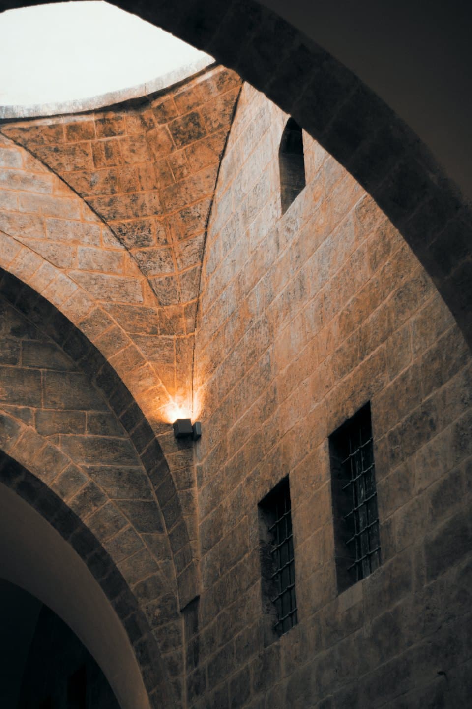 Soffitto a volta in pietra con archi in mattoni e lucernario.