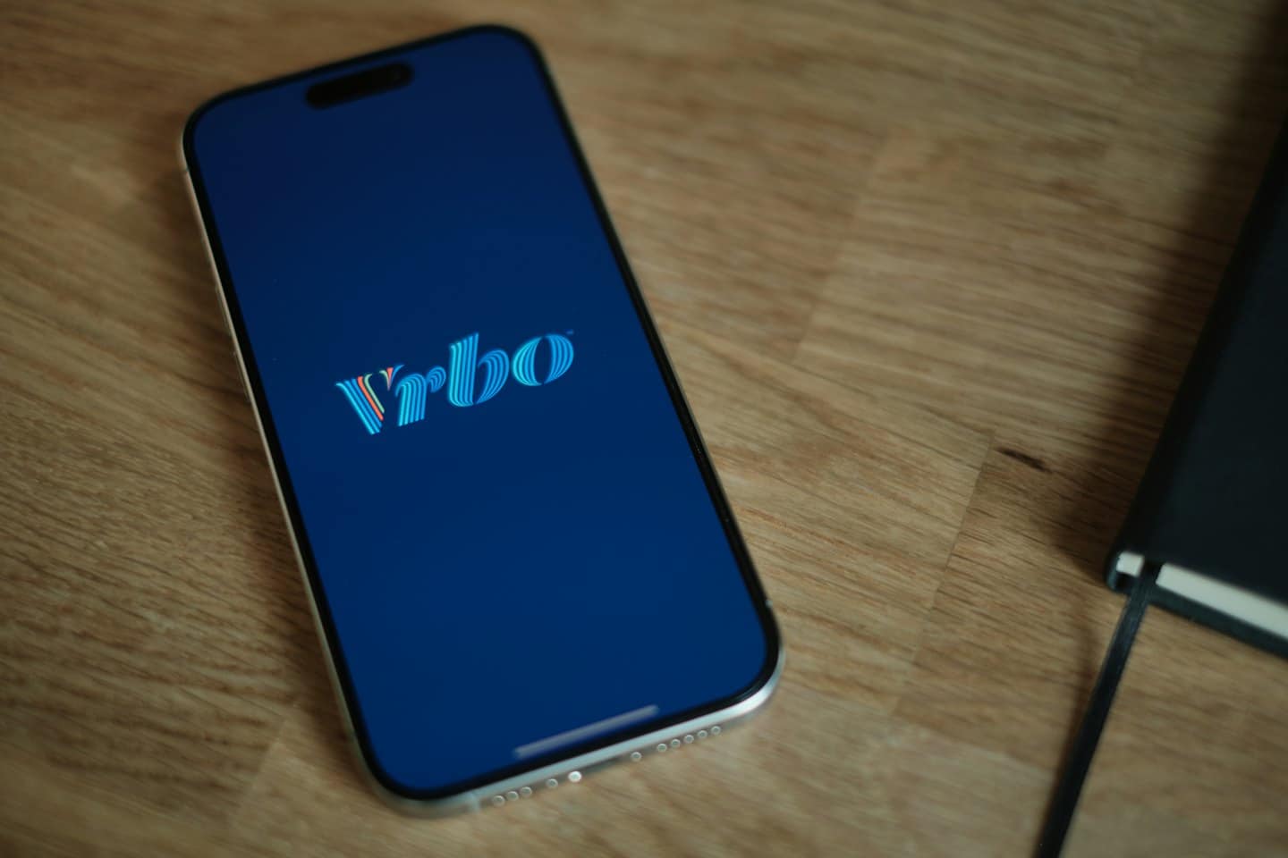 Smartphone con il logo dell'app Vrbo su un tavolo di legno.