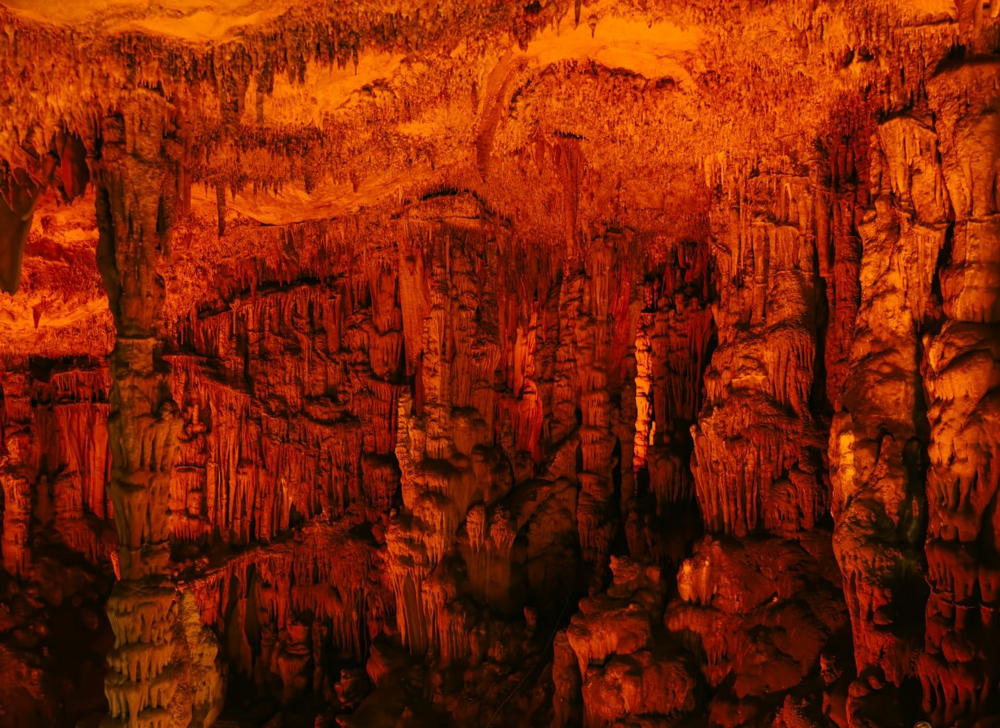 Stalattiti e stalagmiti riempiono l'interno di una grotta rocciosa.