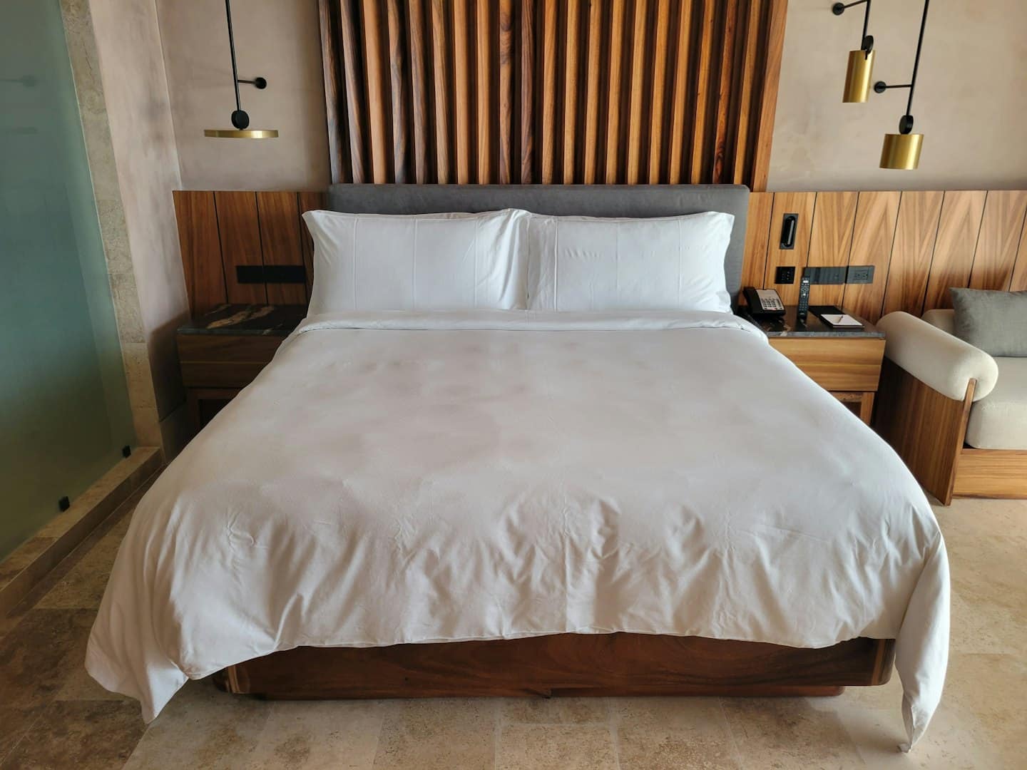 Moderna camera d'albergo con un letto ben fatto e testiera in legno.