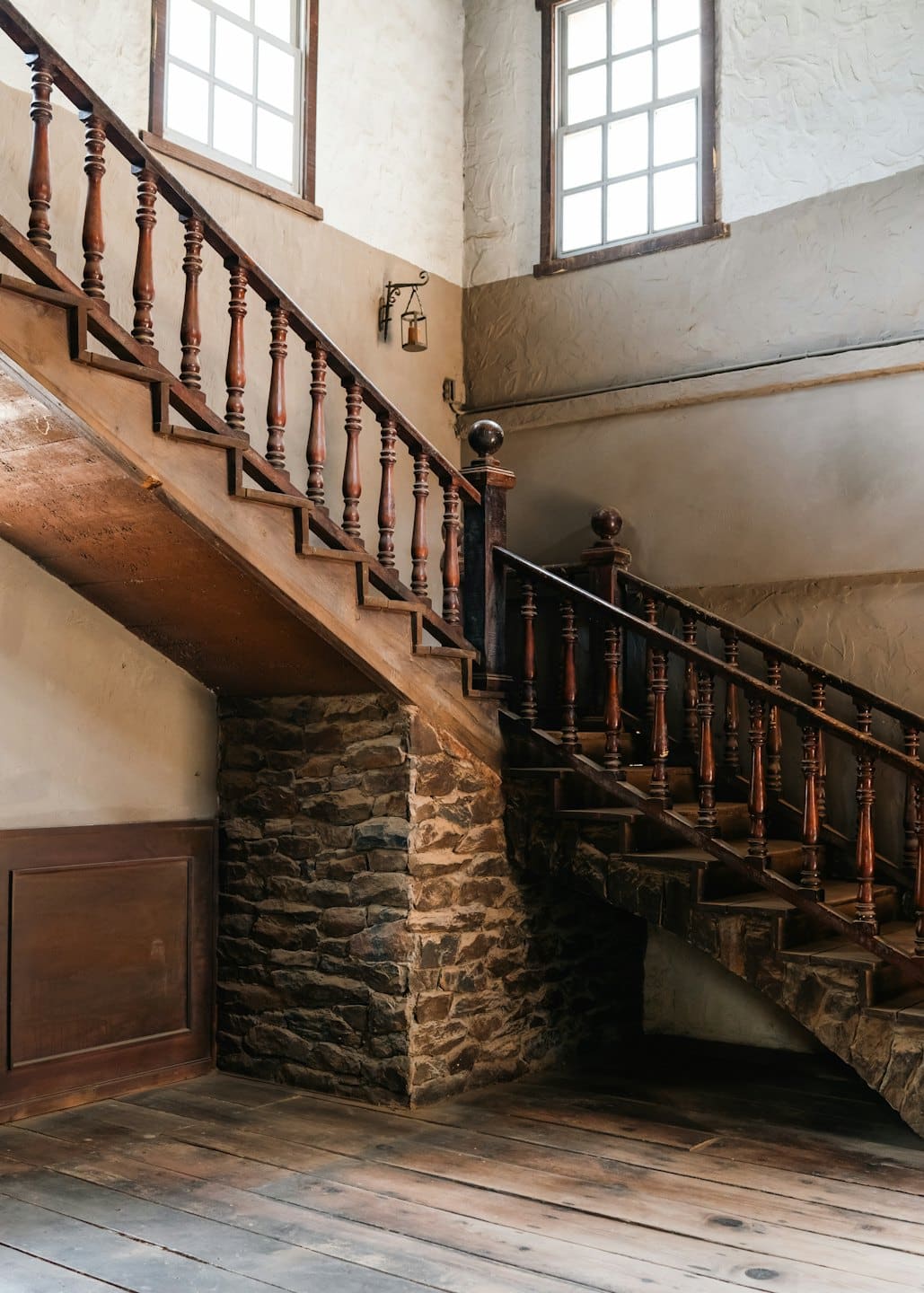 Scala in legno con balaustri torniti sale oltre muri di pietra.
